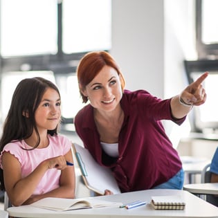 teacher-with-student-at-desk-pointing